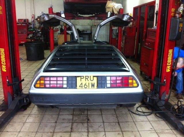 DeLorean DMC-12 with gull-wing doors open in the workshop