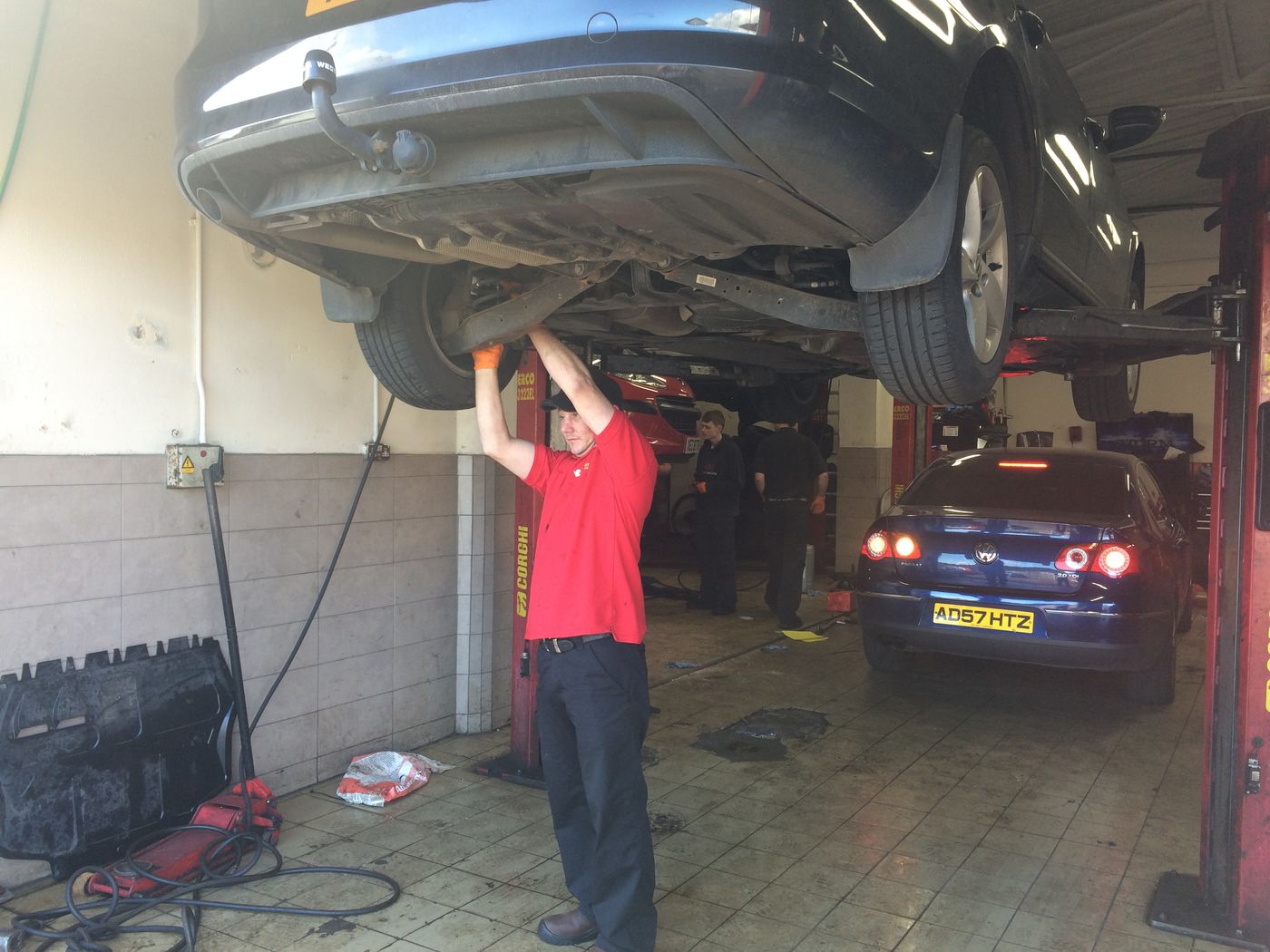 Technician working under a car on a two-post ramp