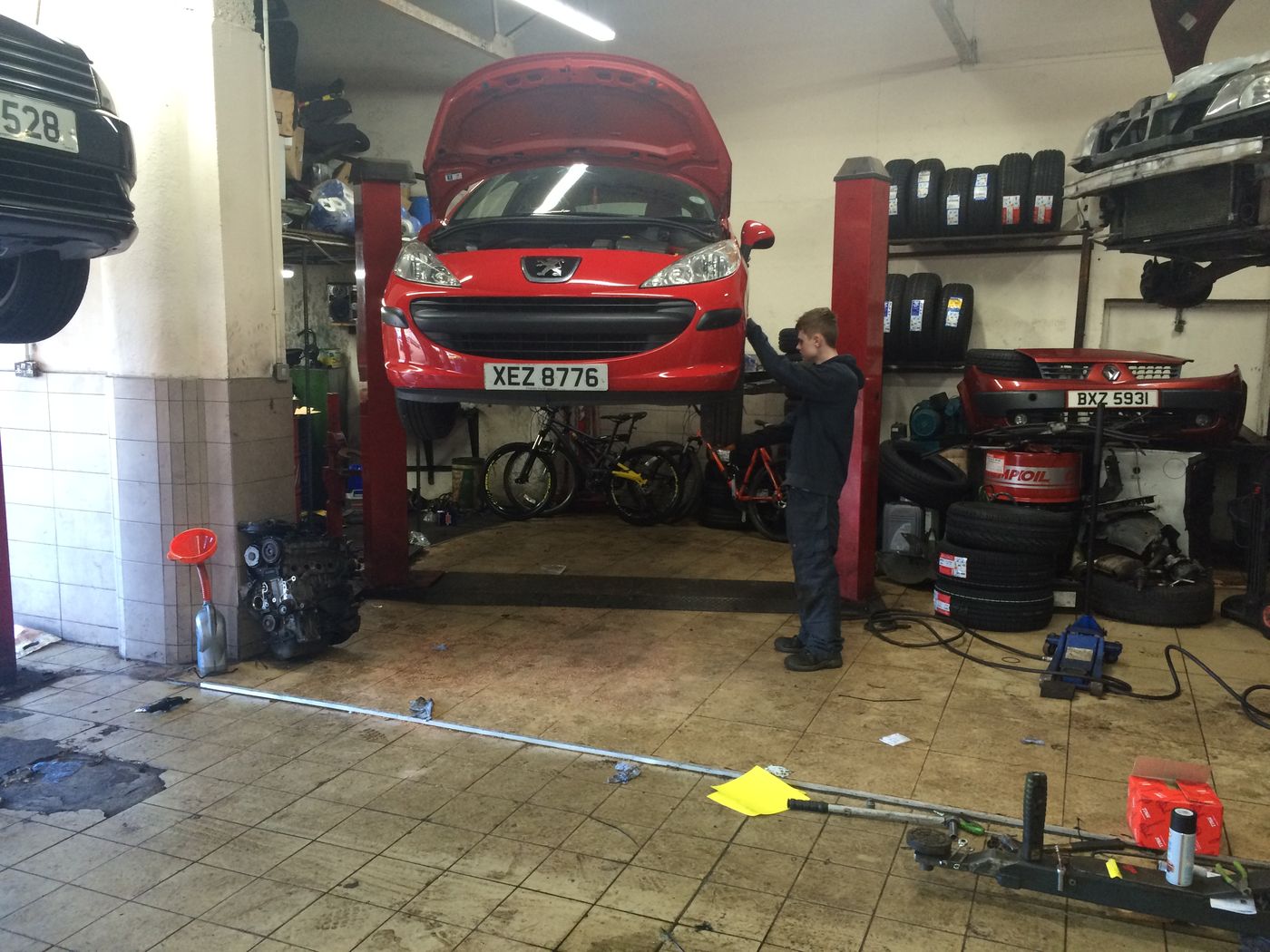 Red Peugeot on a ramp beside the tyre racks