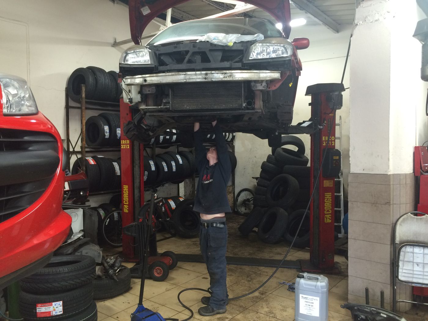 Car raised on a ramp in front of racks of tyres